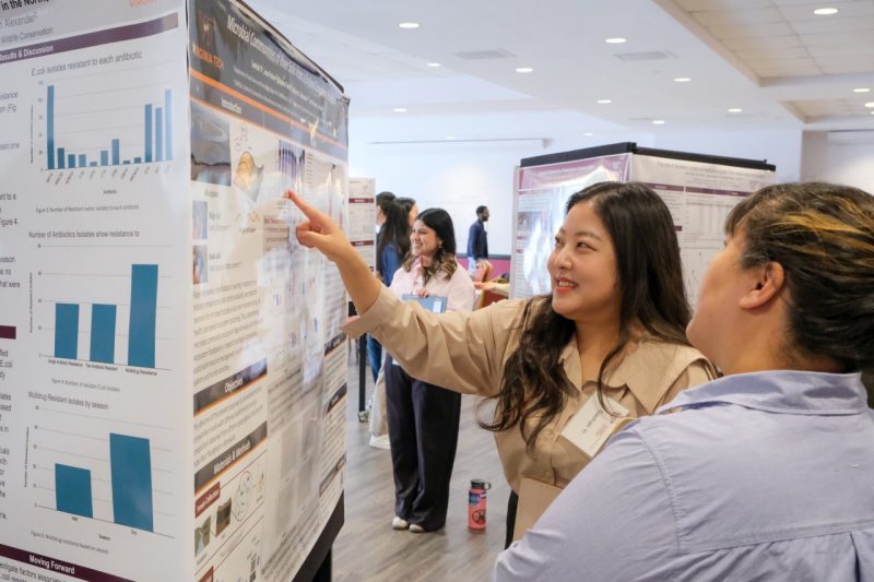 A student presents their research to a judge at the annual student poster competition