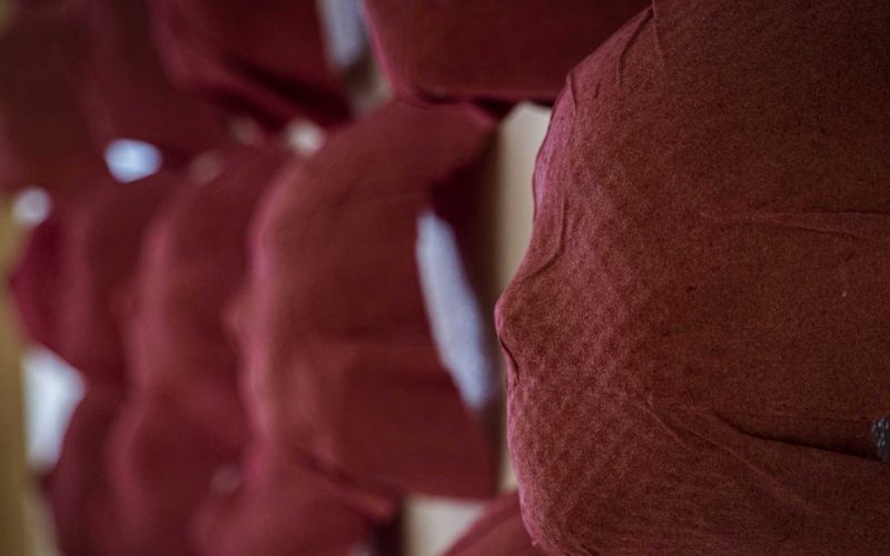 A wall of red colored paper mache masks