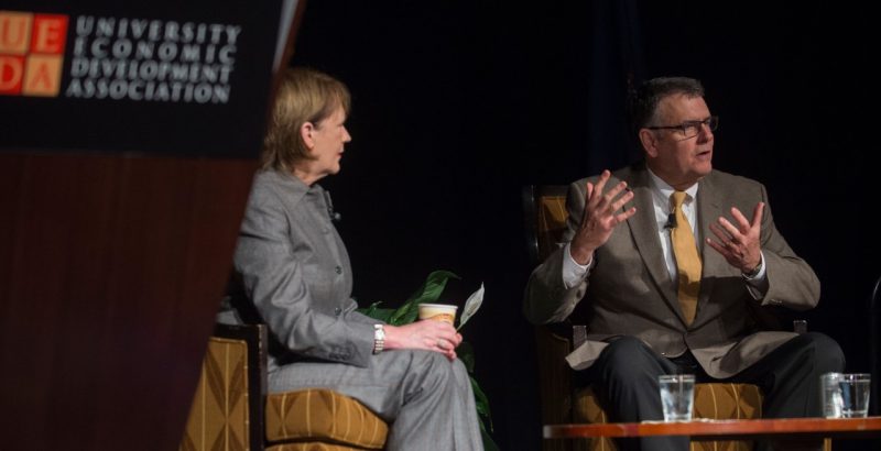 A photo of Nancy Howell Agee and Michael Friedlander sitting on stage and talking.