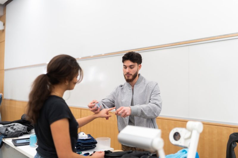 Luis Kruger, director of the Vetement de Rue fashion show, helps student models prepare for the show. Photo by Brandon Kong.