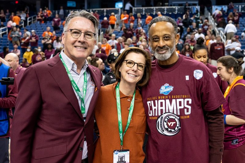 Three people smile at the end of a basketball game 