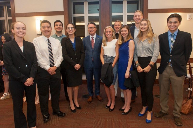 Young men and women in business wear smile at the camera.