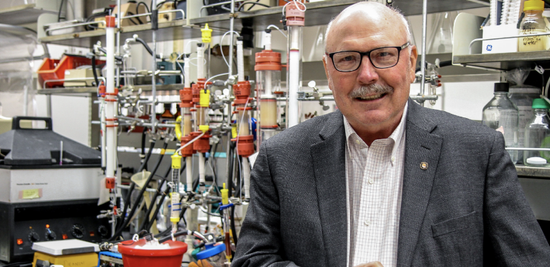 Dennis Dean, University Distinguished Professor in his lab at Fralin Hall. Bright red, blue, and yellow tubes are in the background.